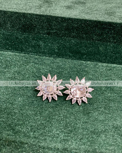 Silver flower-shaped earrings on a green fabric background