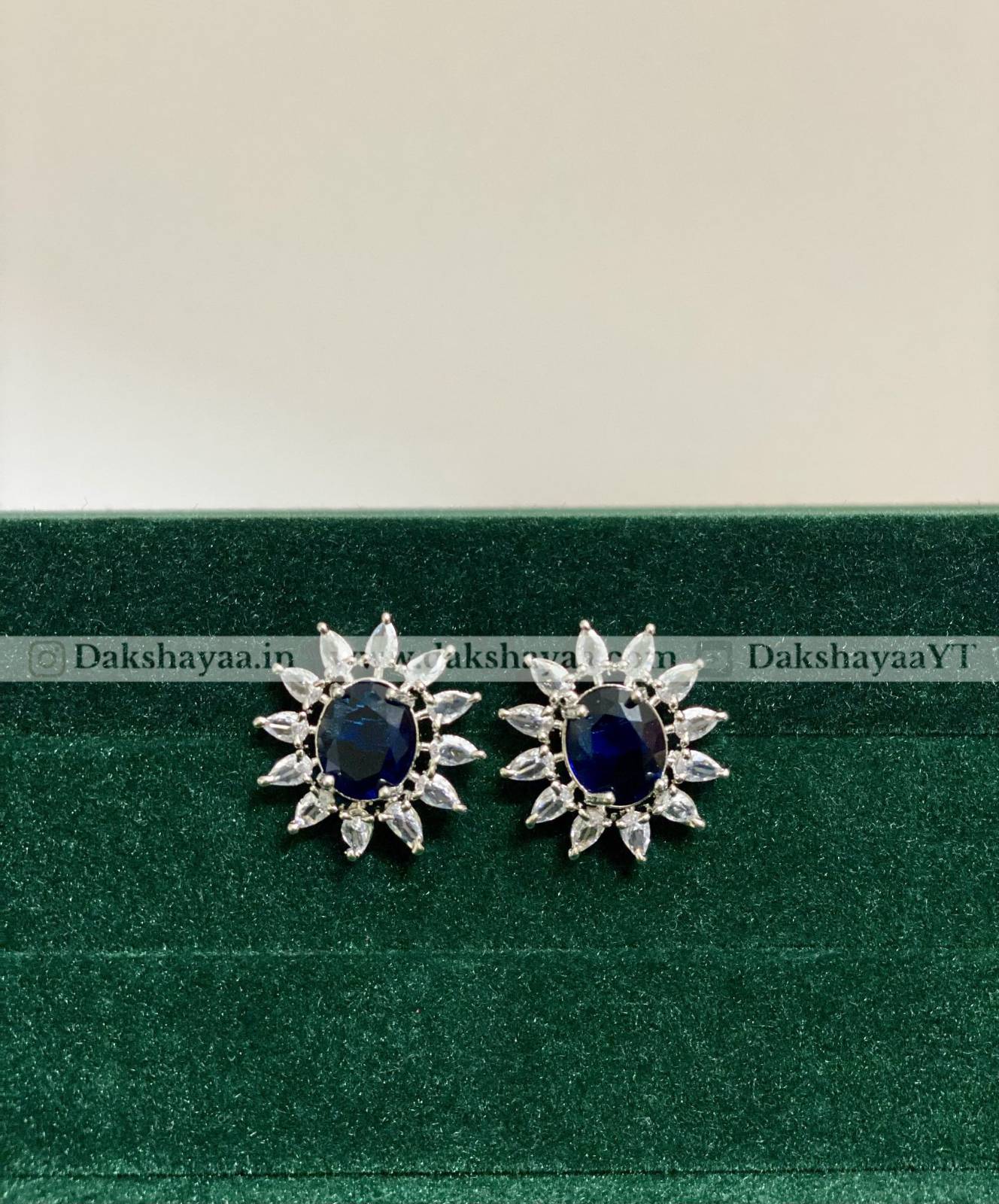 Pair of silver earrings with blue gemstones on a green and beige background