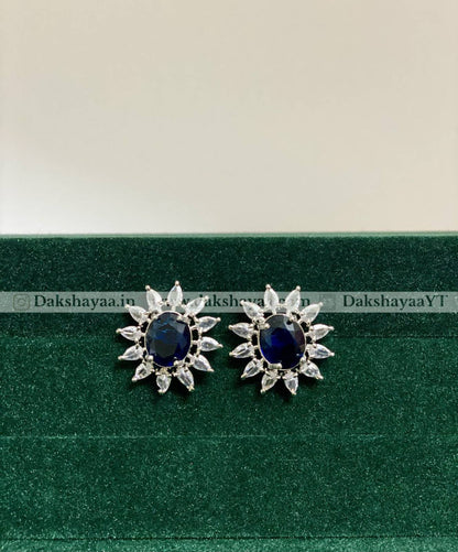 Pair of silver earrings with blue gemstones on a green and beige background