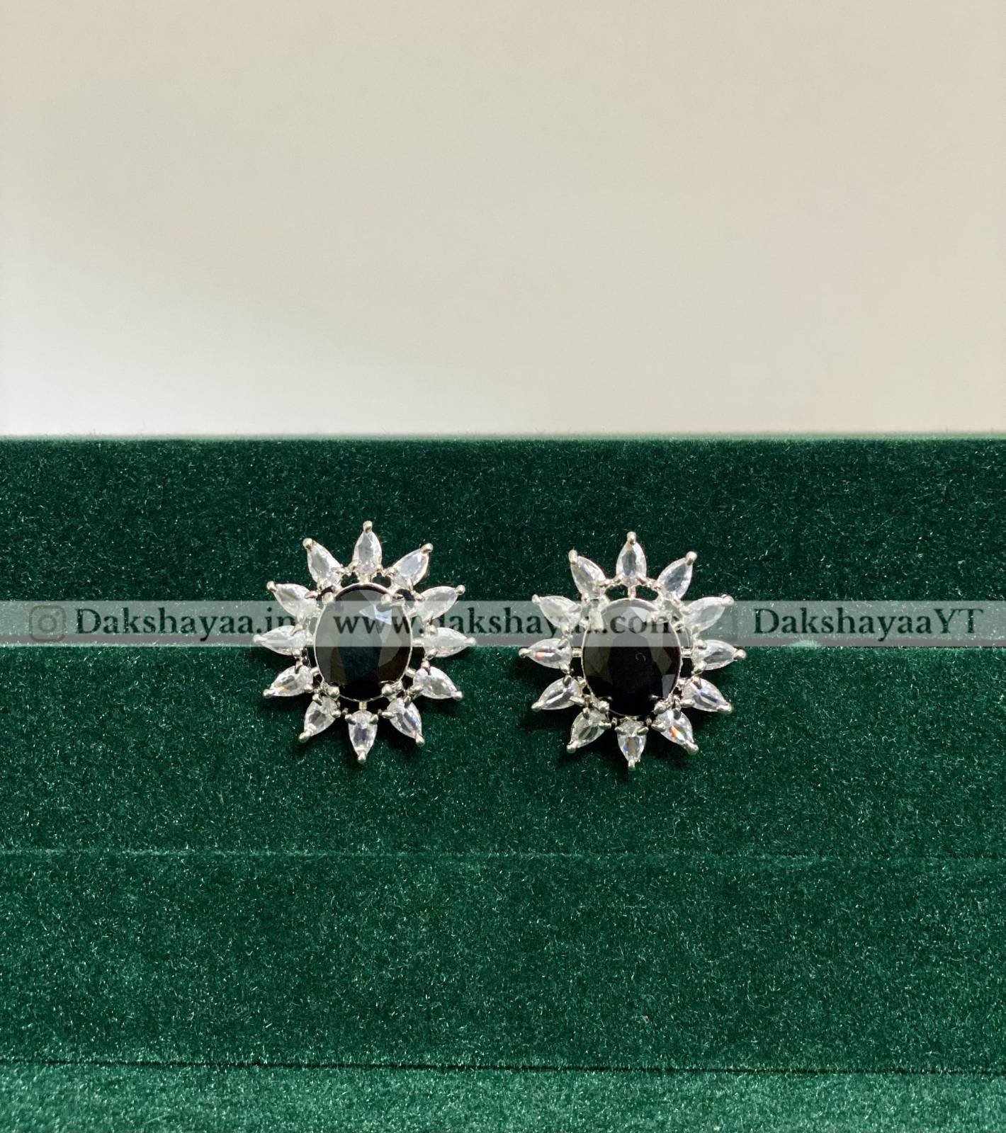 Pair of silver earrings with black gemstones on a green cushion