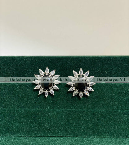 Pair of silver earrings with black gemstones on a green cushion