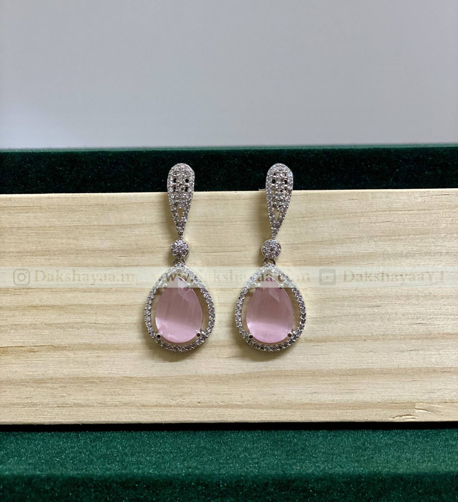 Pair of earrings with pink gemstones on a wooden surface
