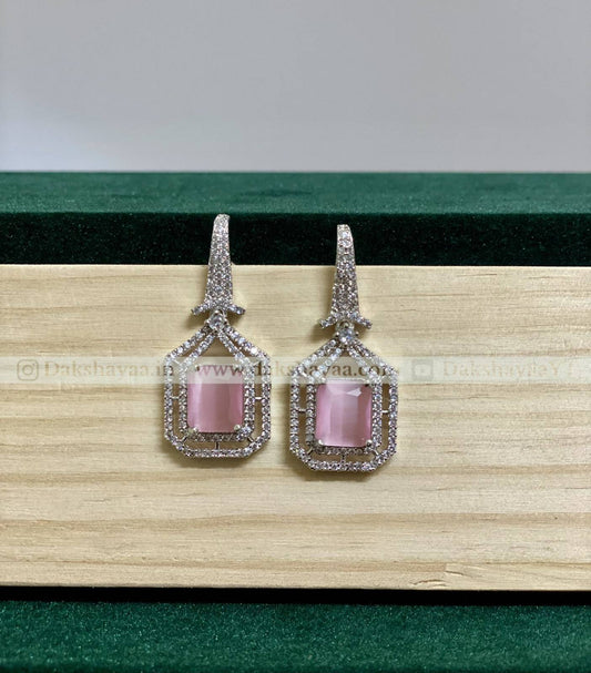 Pair of earrings with pink gemstones on a wooden surface