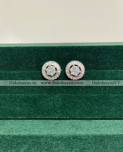 Pair of silver earrings with gemstones on a green velvet stand.