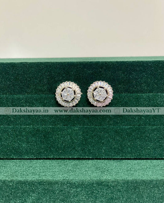 Pair of silver earrings with gemstones on a green velvet stand.