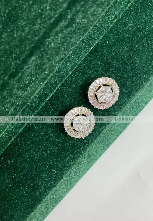 Pair of silver earrings with gemstones on a green fabric background