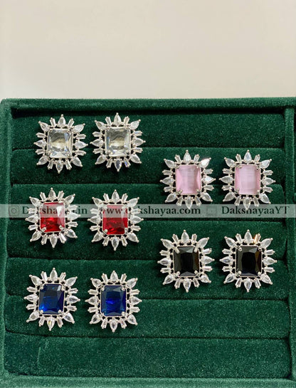Set of silver earrings with gemstones on a green velvet display box. white, pink, red, black and blue