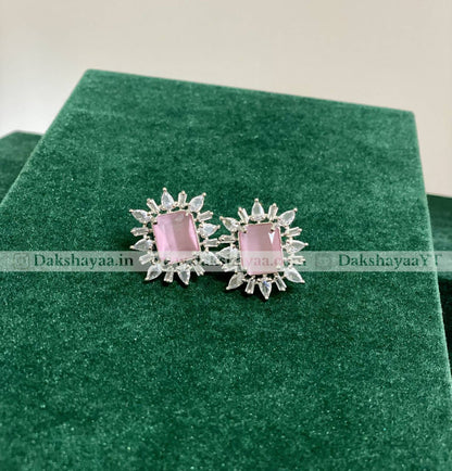 Pair of earrings with pink gemstones on a green velvet surface