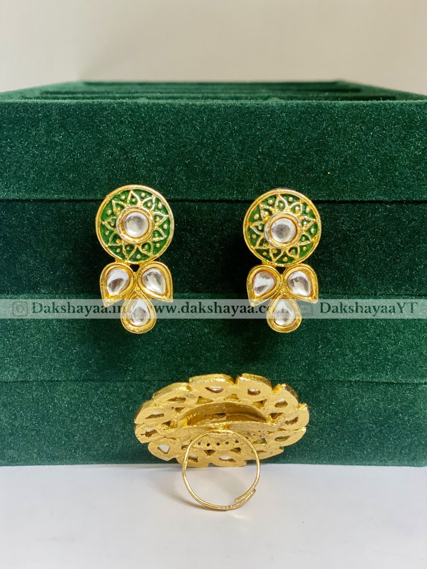 Gold and green earrings on a green velvet box