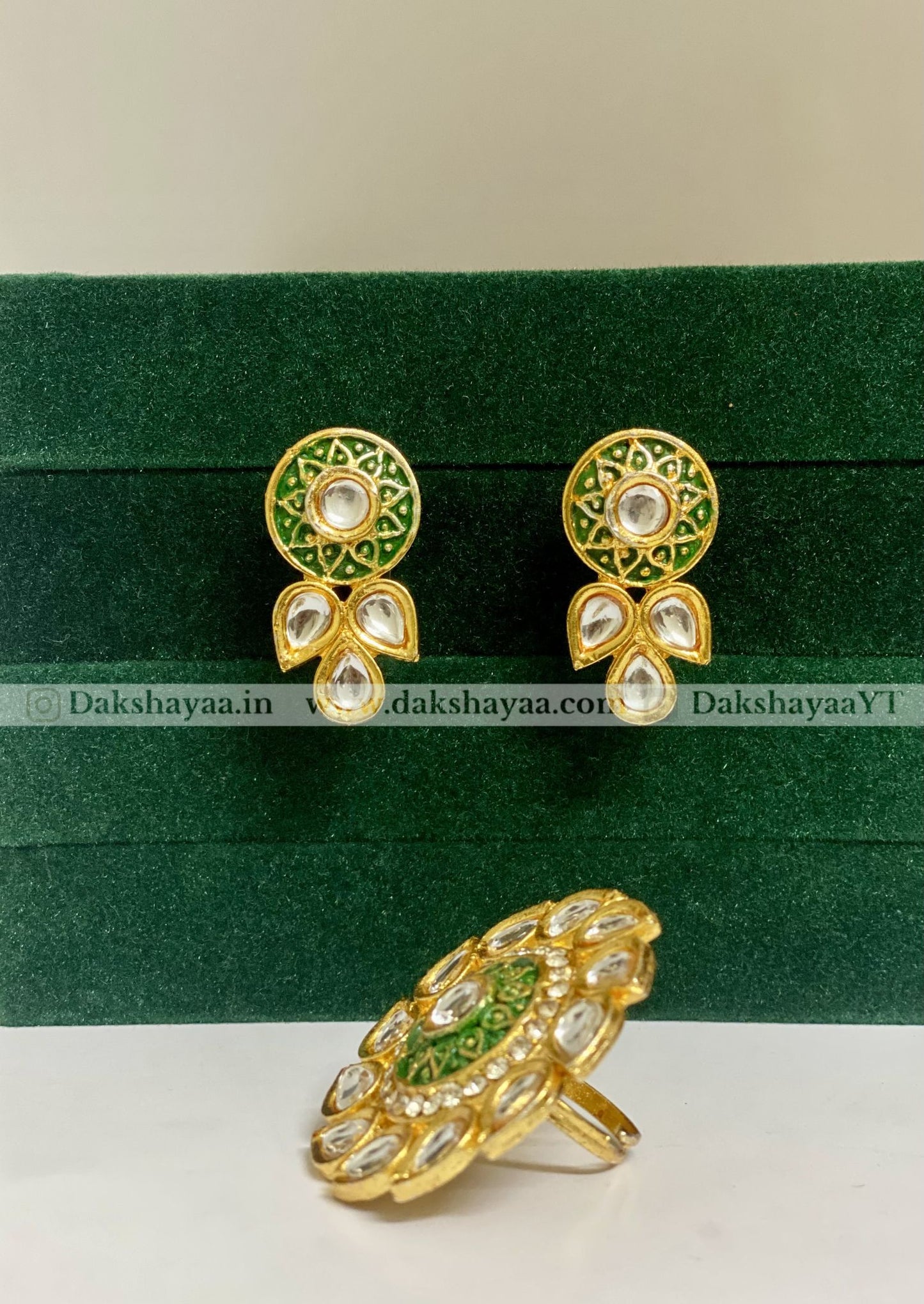 Gold and green earrings on a green and white background