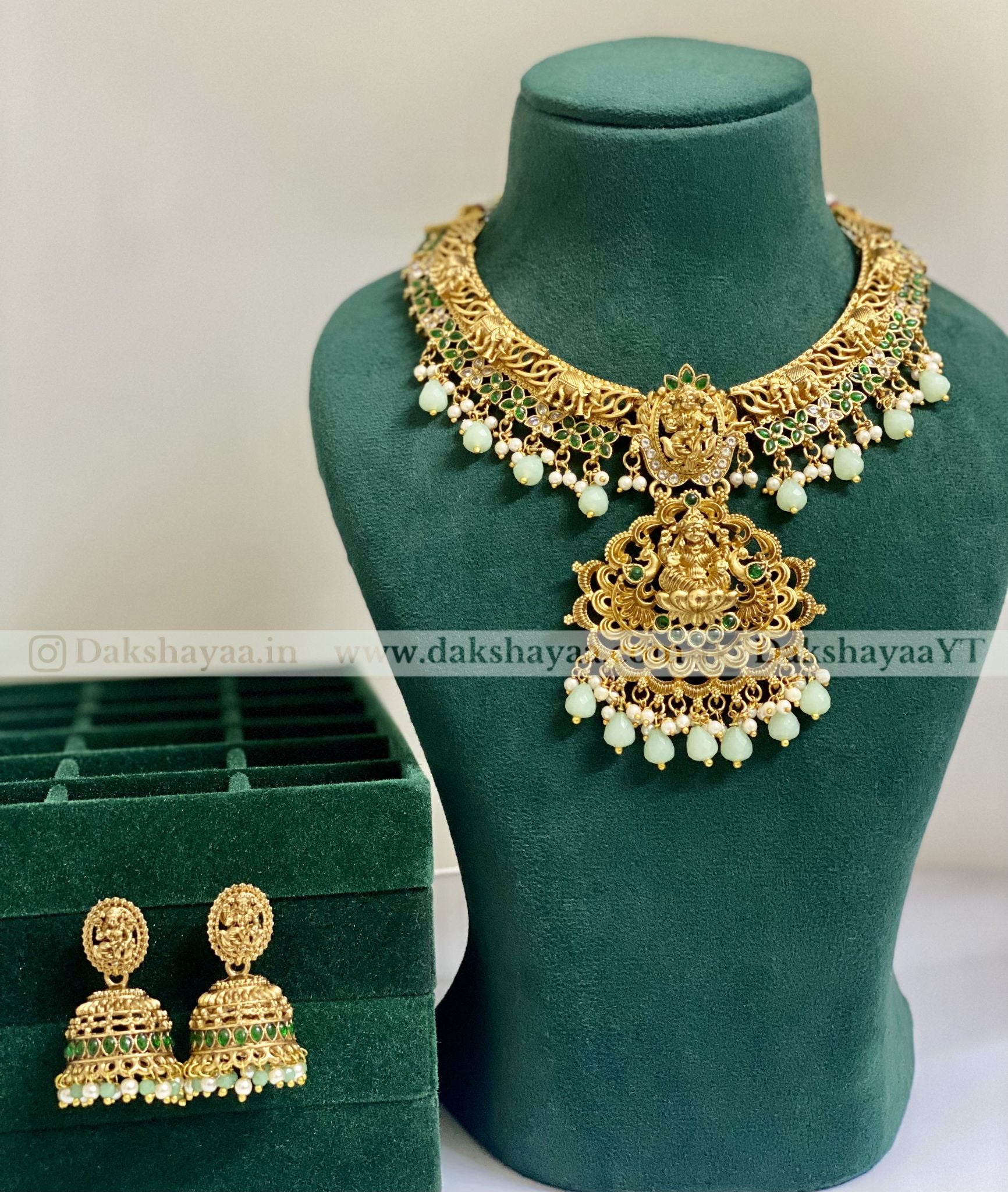 mint green Gold necklace and earrings on a green mannequin with a green box in the background