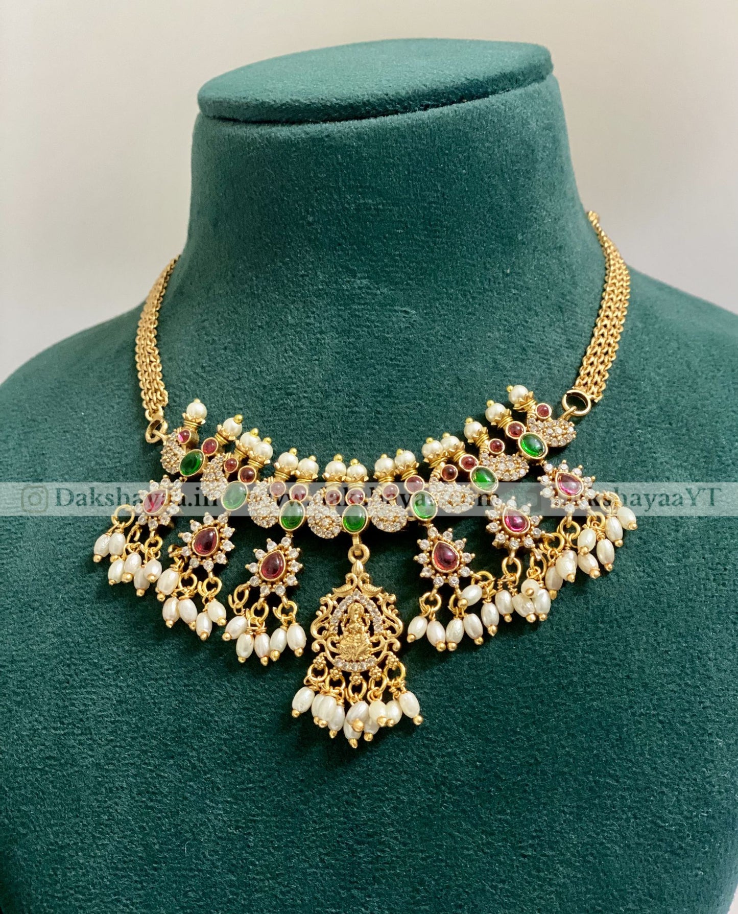 Gold necklace with pearls and gemstones on a green velvet mannequin