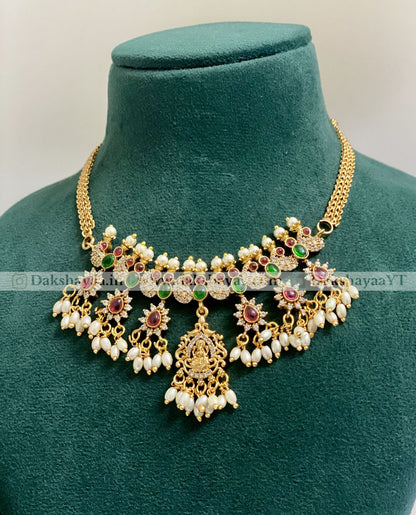 Gold necklace with pearls and gemstones on a green velvet mannequin