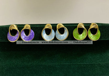 Set of colorful earrings on a green stand with visible branding.