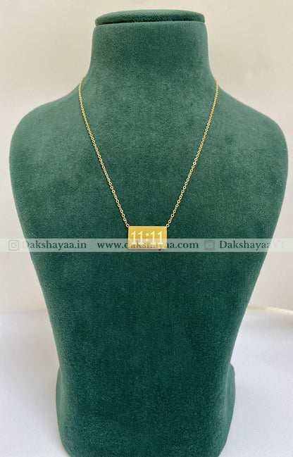Gold necklace on a green mannequin bust with visible brand name.
