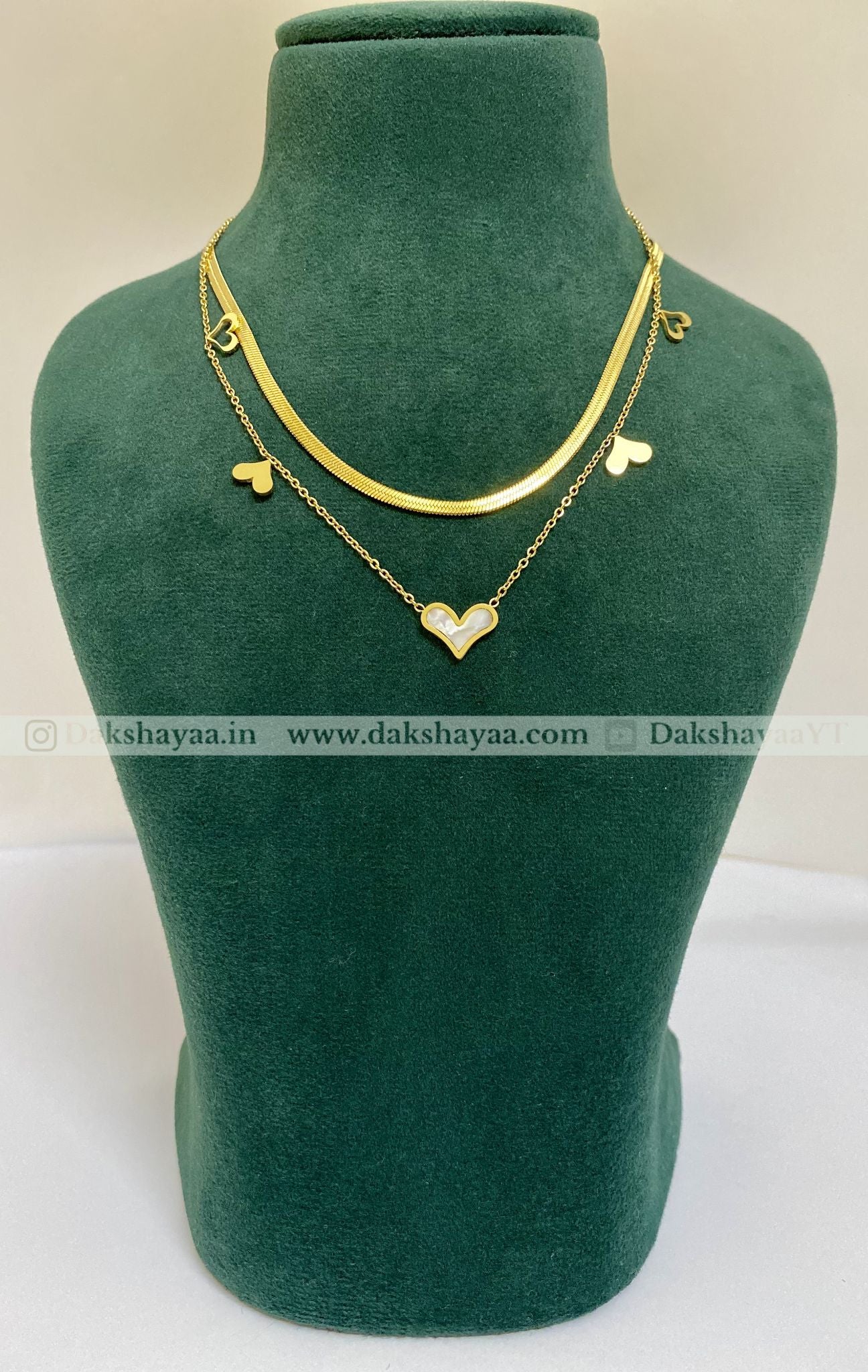 Gold necklace with heart pendants on a green mannequin bust.