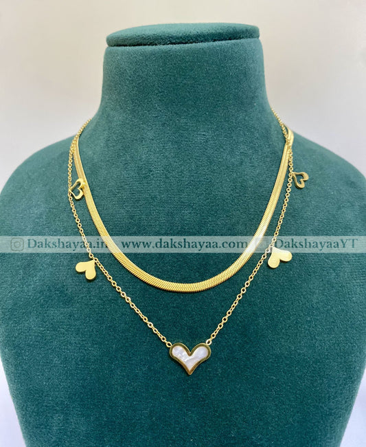 Gold necklace with heart-shaped pendants on a green mannequin bust.
