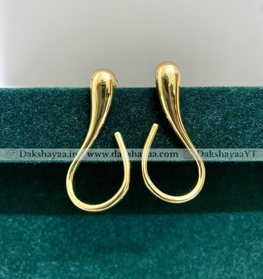 Gold earrings on a green and white background