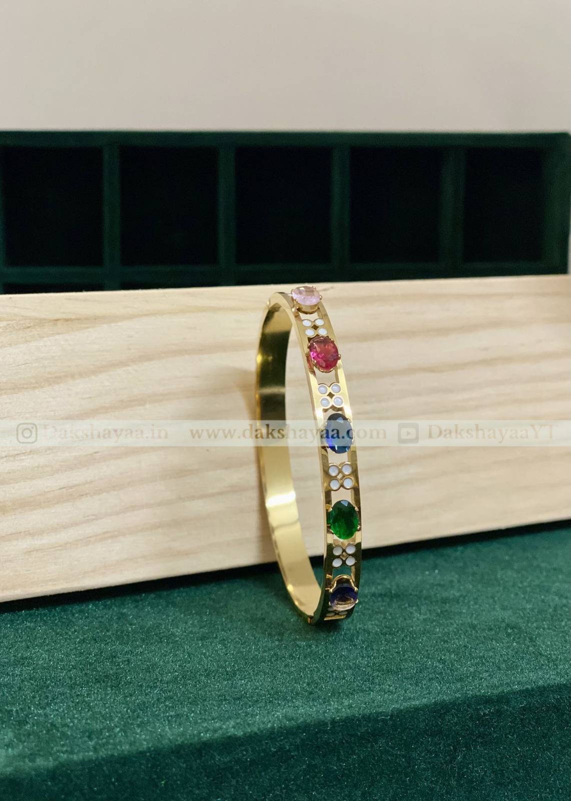 Gold bracelet with colorful gemstones on a wooden surface