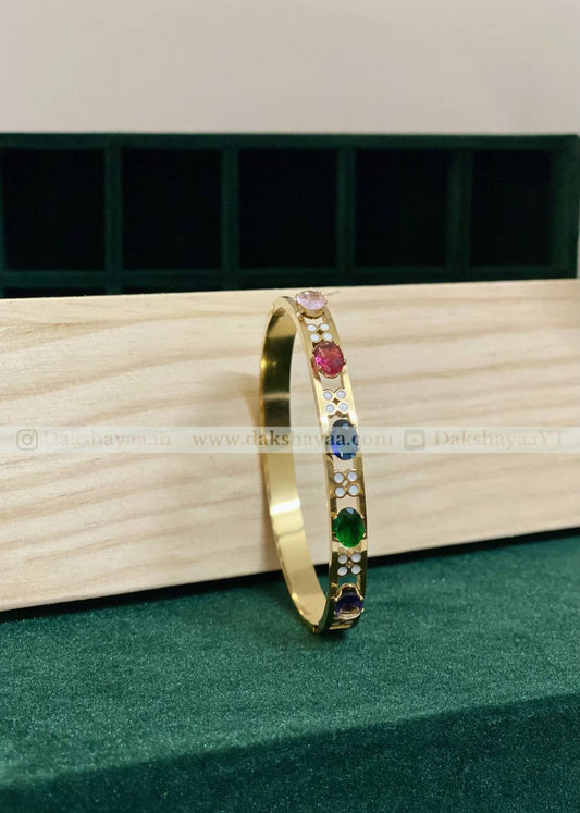 Gold bracelet with colorful gemstones on a wooden surface
