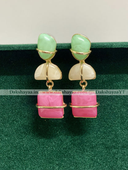 Pair of earrings with green and pink stones on a green background