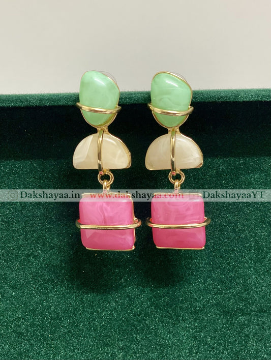 Pair of earrings with green and pink stones on a green background