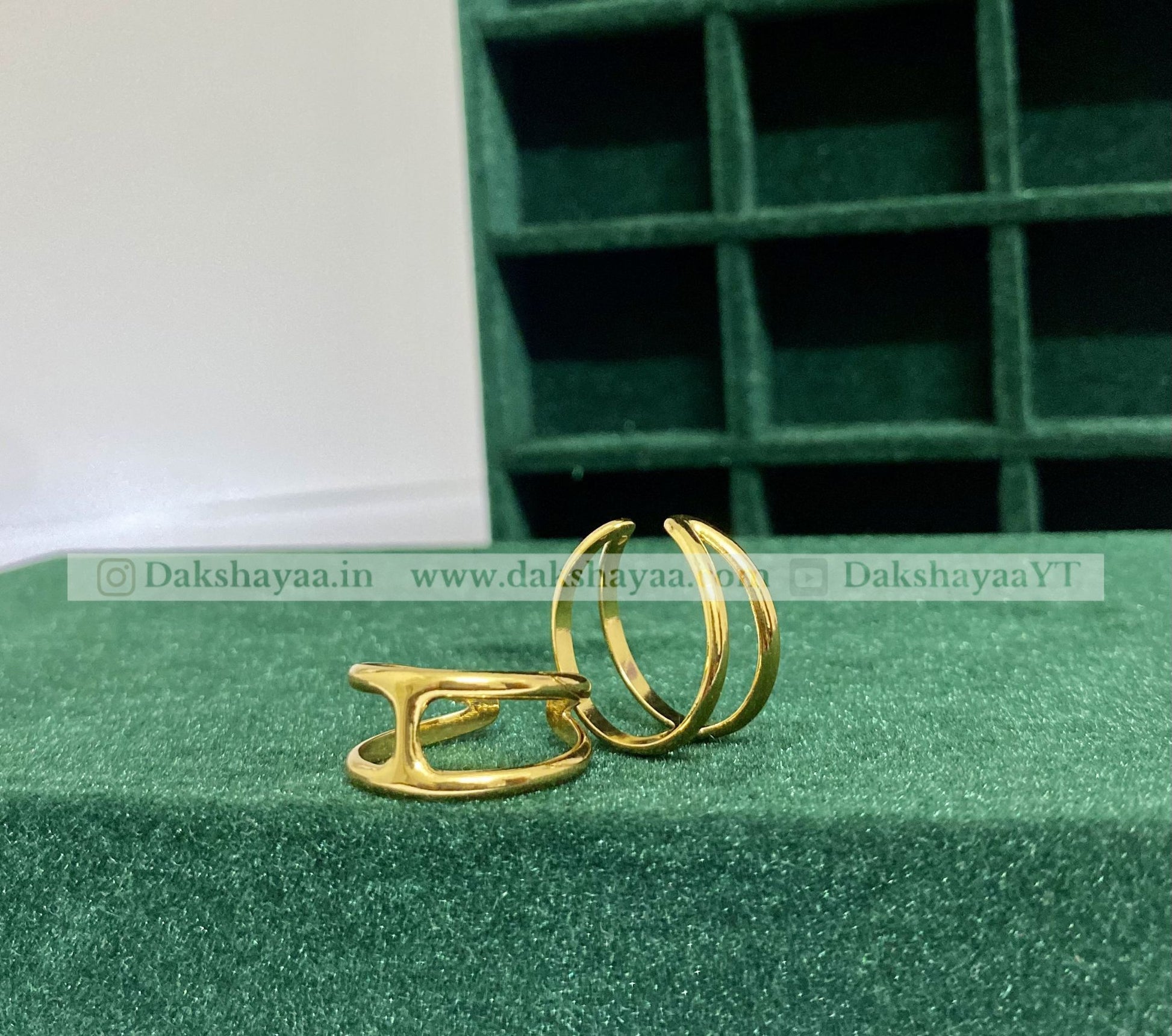Gold hoop earrings on a green textured surface with a grid background