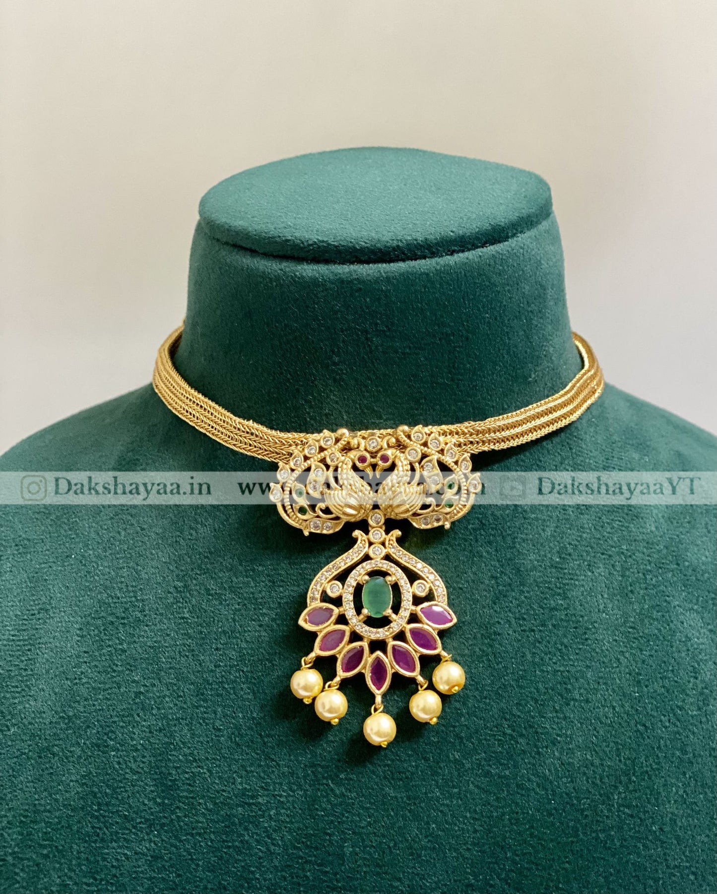 Gold necklace with a pendant on a green velvet stand