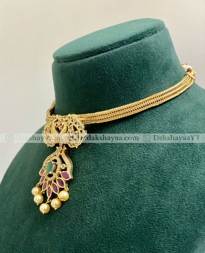 Gold necklace with pendant on a green velvet stand