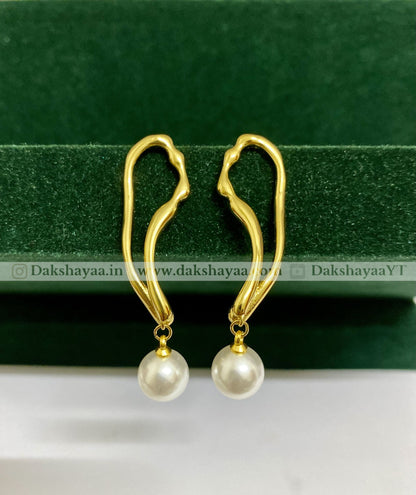 Gold earrings with pearl drops on a green background