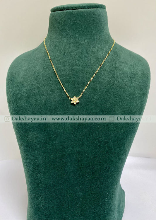 Gold necklace with a star pendant on a green mannequin bust, brand 'Dakshayaa' visible.