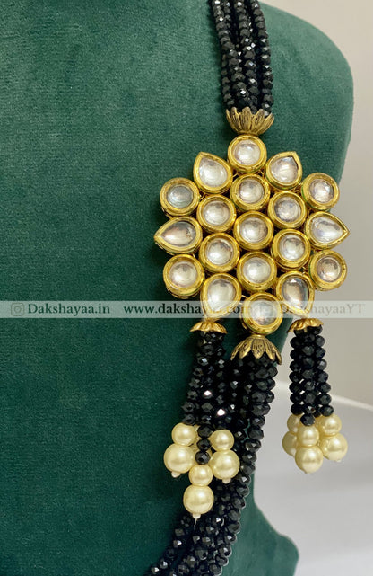 Decorative necklace with black and gold beads on a green background