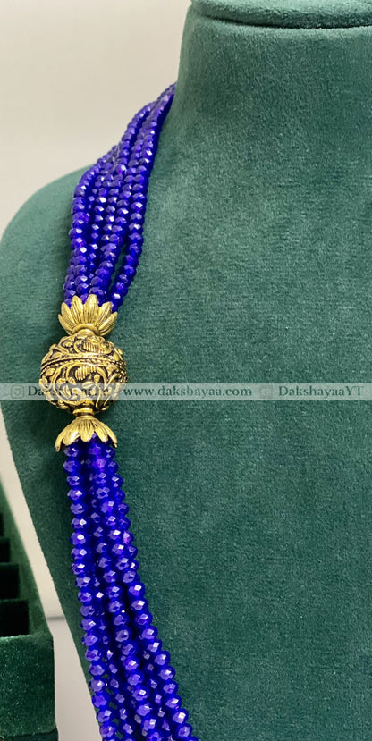 Blue beaded necklace with a gold clasp on a green mannequin