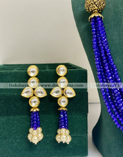 Pair of earrings with blue and gold accents on a green stand.