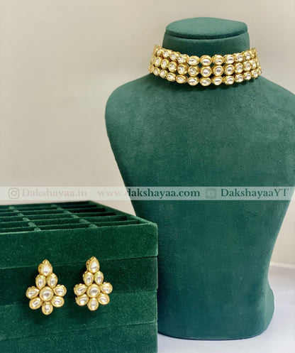 Gold jewelry set with earrings and a necklace on a green mannequin and box.