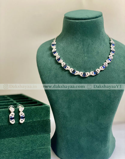 Jewelry set with necklace and earrings on a green mannequin and box, brand 'Dakshayaa' visible.