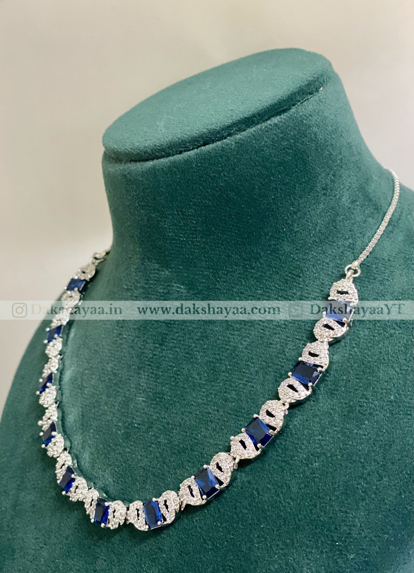 Necklace with blue and silver design on a green mannequin