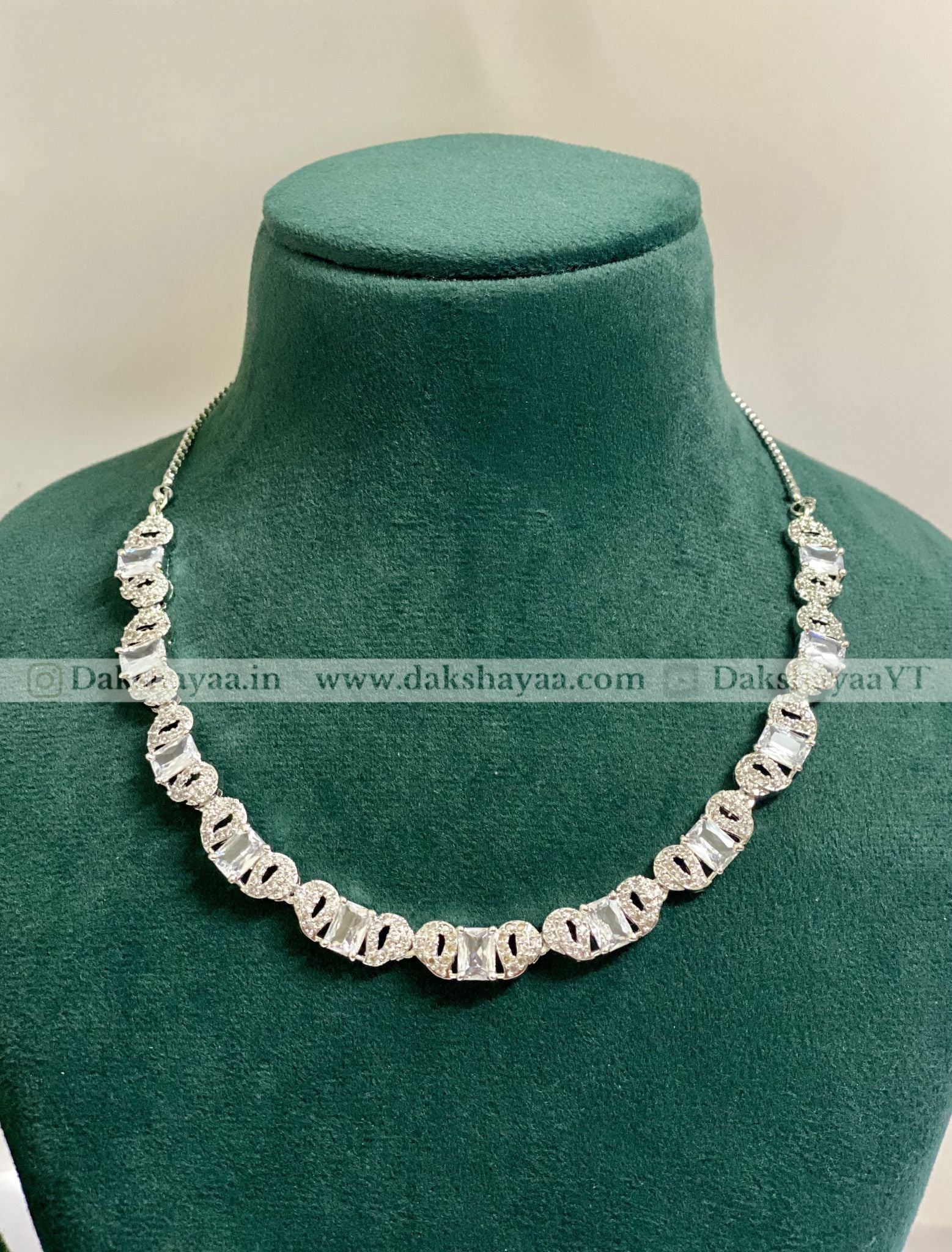 Silver necklace on a green mannequin with visible branding.