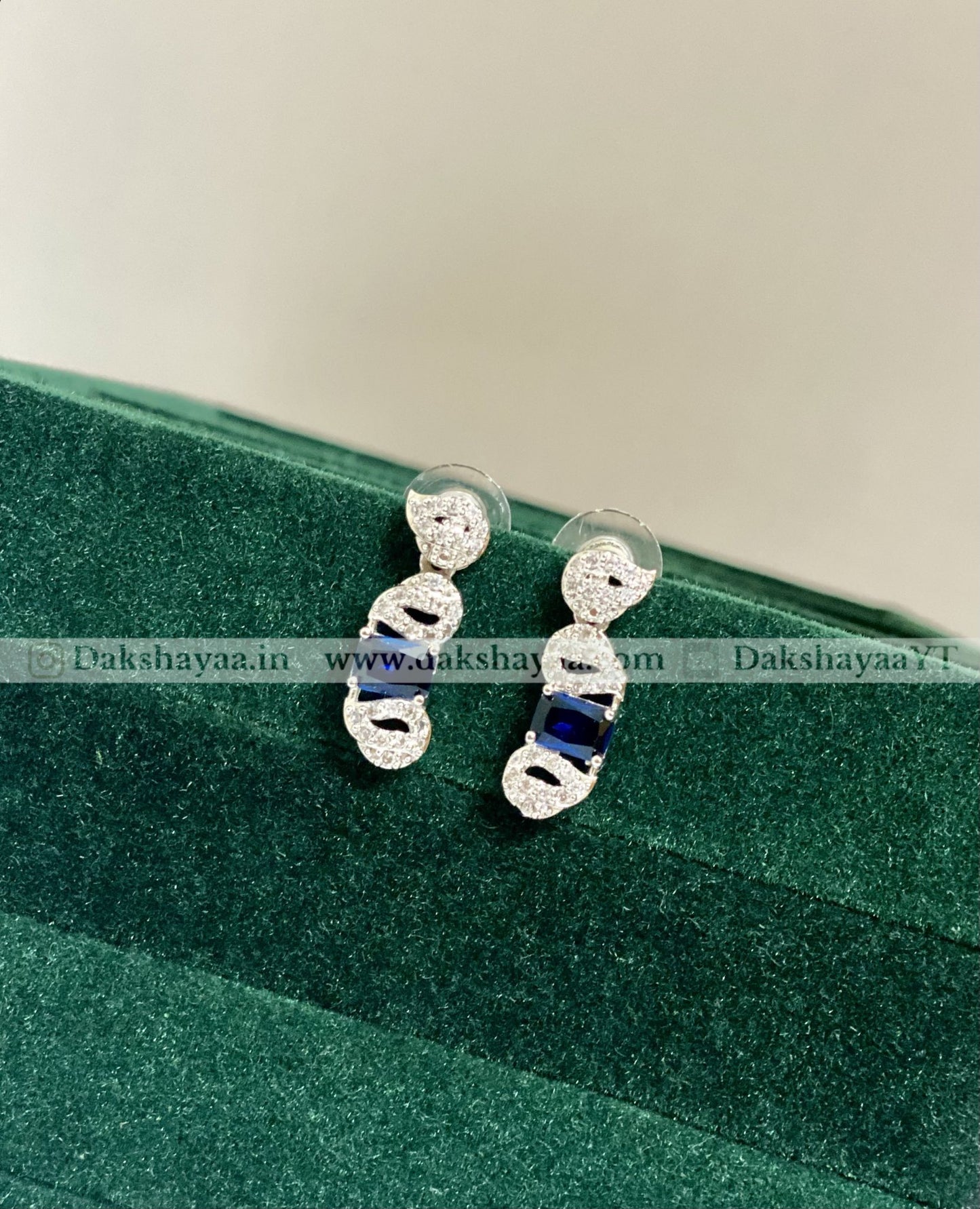 Silver earrings with blue stones on a green velvet surface