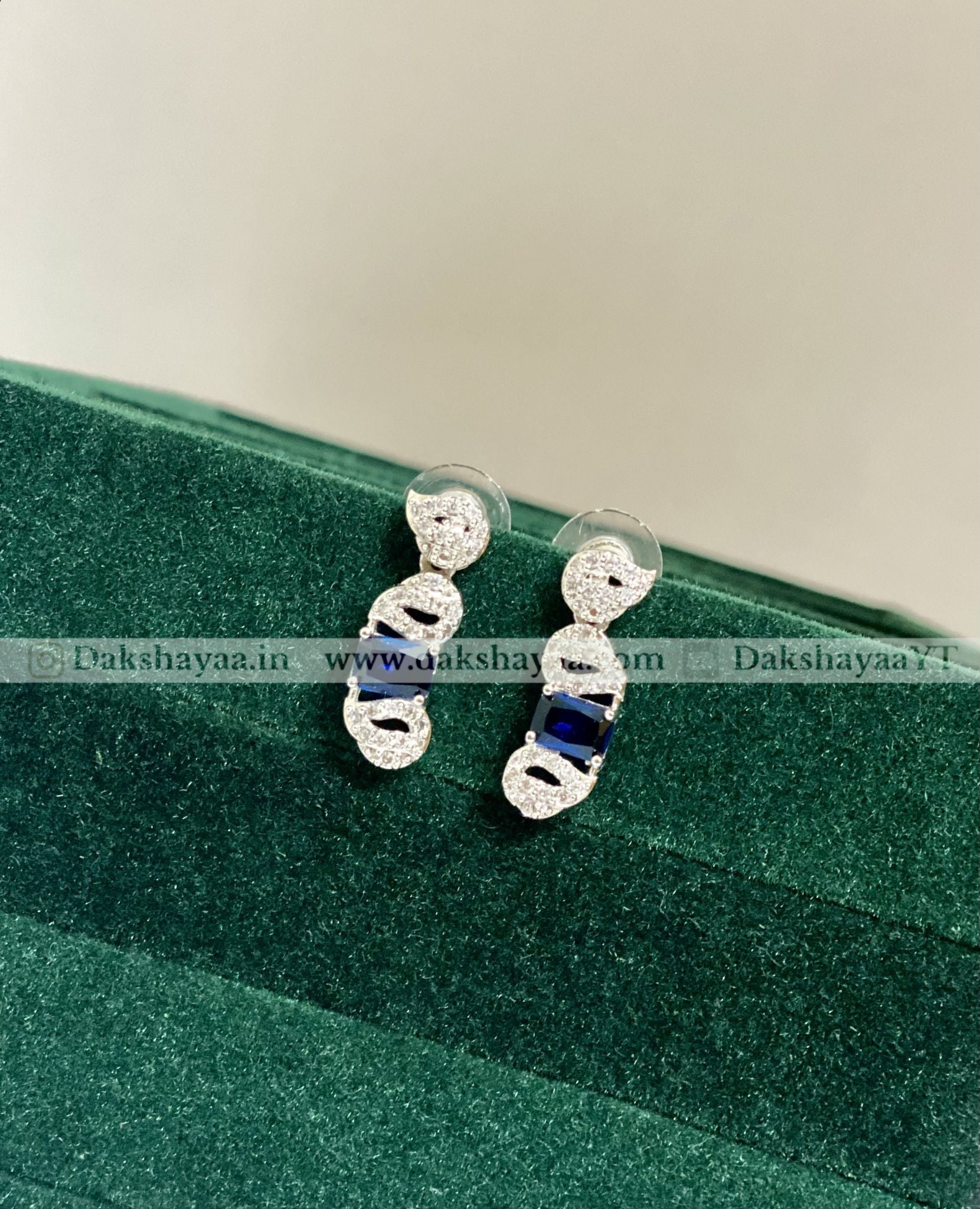 Silver earrings with blue stones on a green velvet surface
