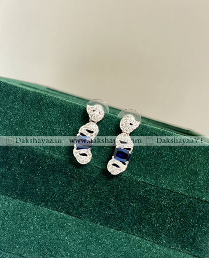 Silver earrings with blue stones on a green velvet surface