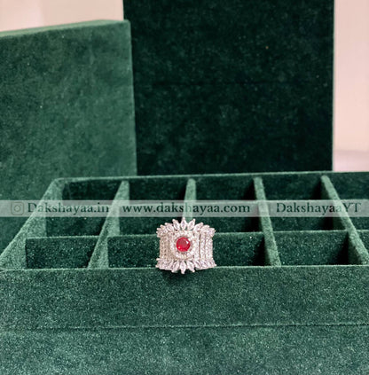 Silver ring with a red gemstone on a green velvet display box