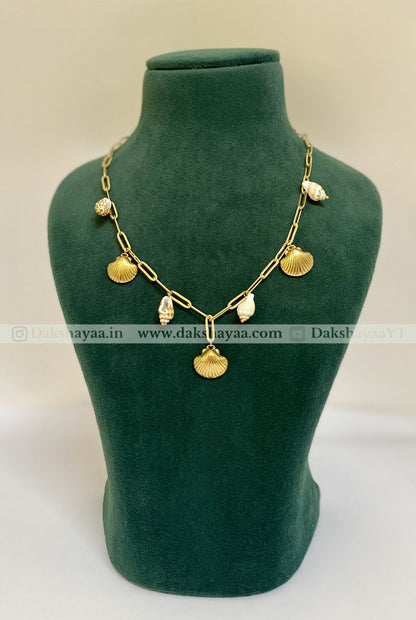Gold necklace on a green mannequin bust with dakshayaa visible brand watermark.