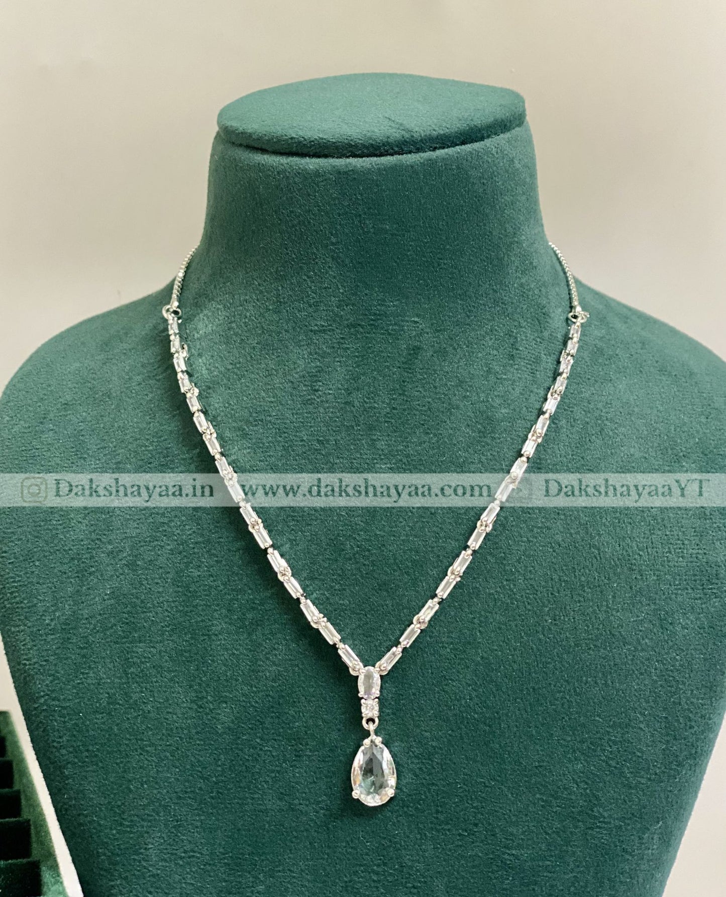 Necklace with a teardrop pendant on a green mannequin bust