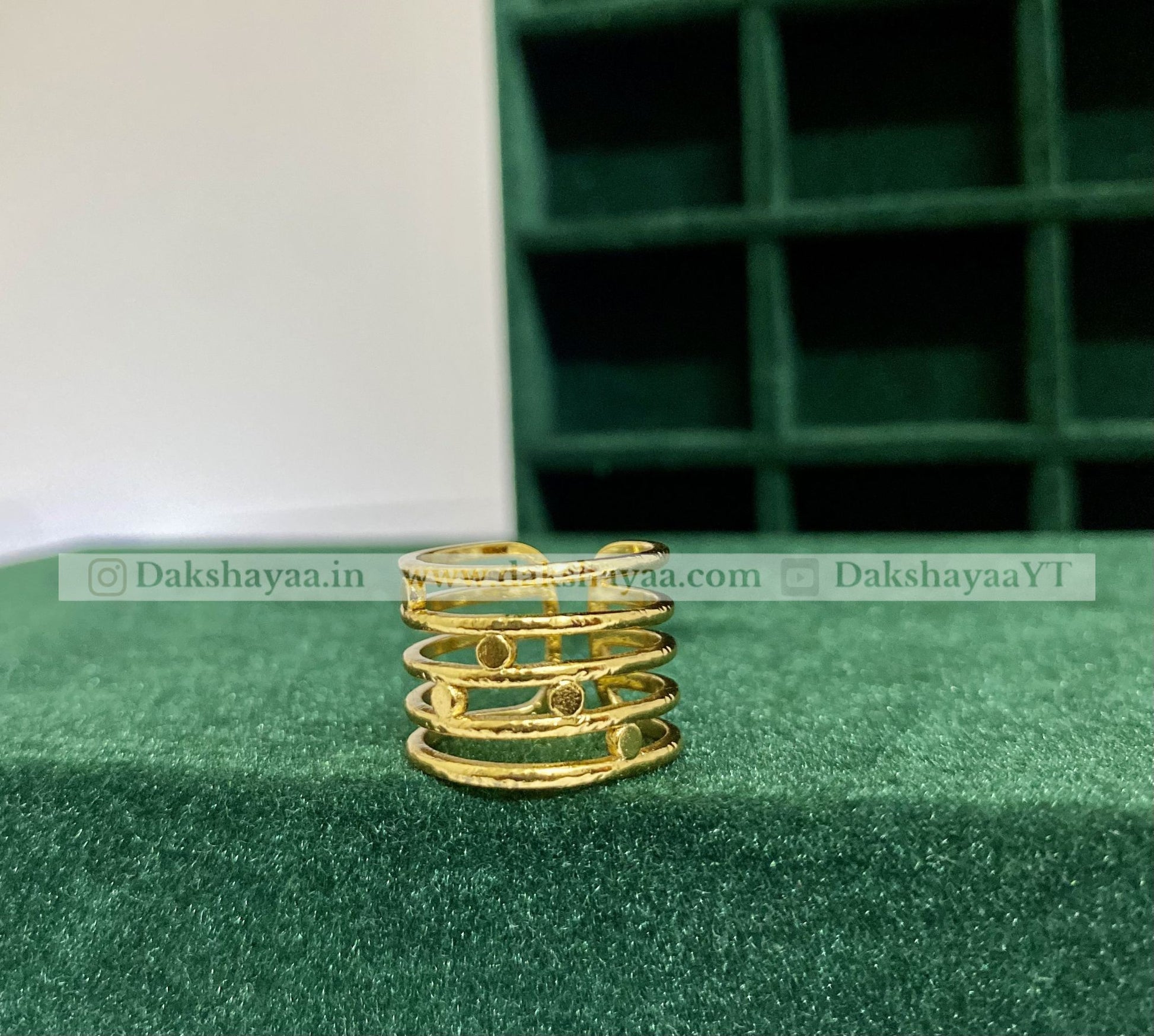 Gold spiral ring on a green surface with a green grid background