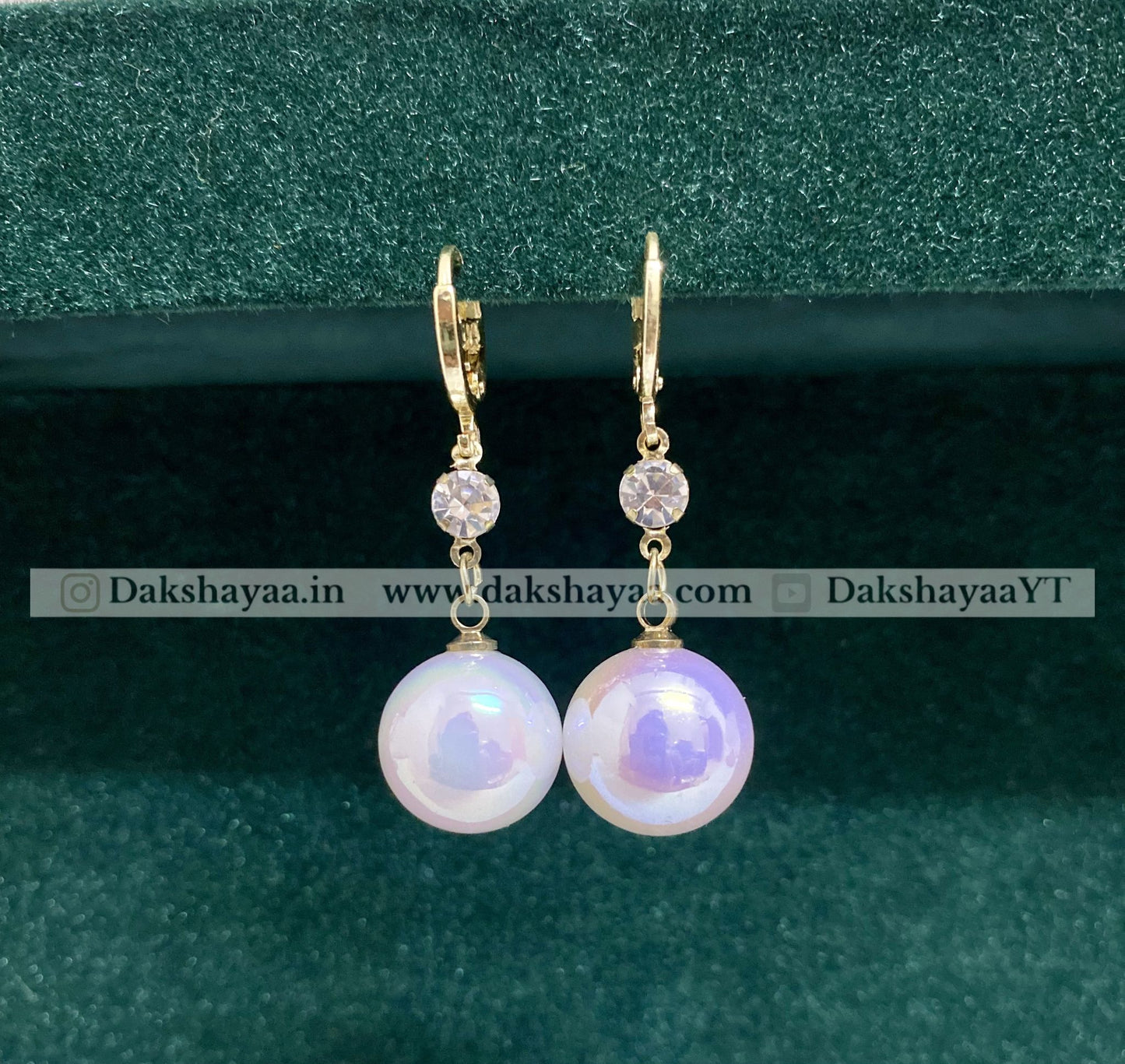 Pearl earrings with gold hooks on a green background