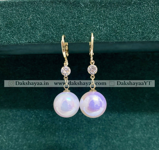 Pearl earrings with gold hooks on a green background