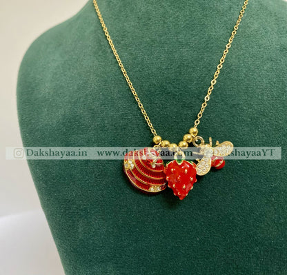 Gold necklace with red and gold pendants on a green mannequin