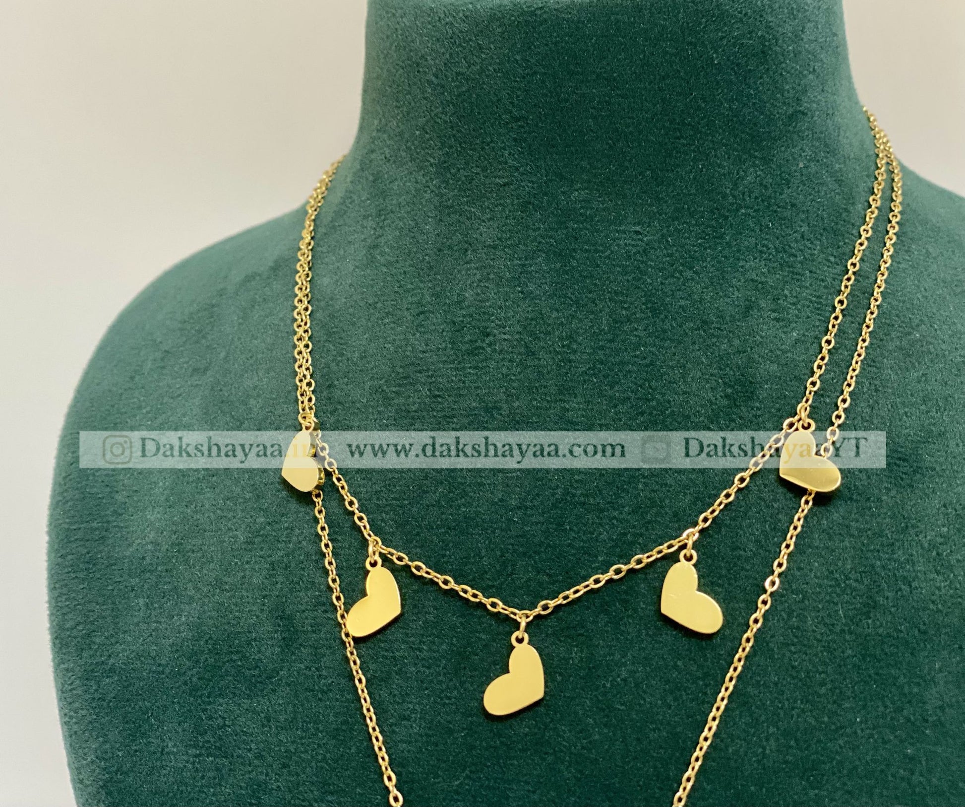Gold necklace with heart pendants on a green mannequin
