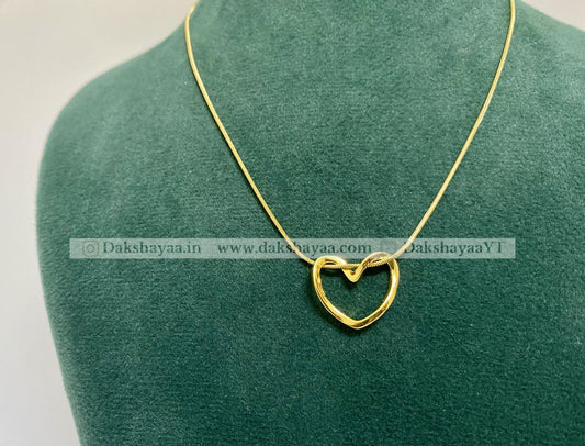 Gold heart-shaped pendant on a green mannequin with visible branding.